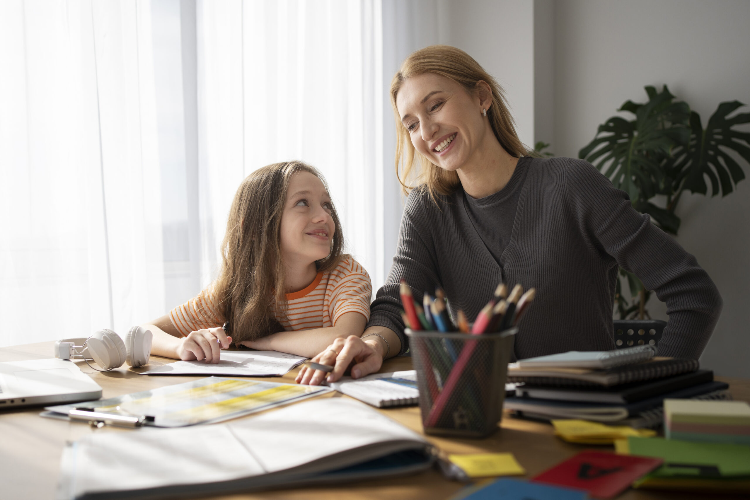 A parent encouraging their child to solve math homework independently at the kitchen table.